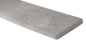 Zbliżenie na narożnik wewnętrznego parapetu w okleinie o strukturze jasnego betonu architektonicznego. Widoczna matowa powierzchnia z delikatnymi, naturalnymi przetarciami oraz bezpieczny, zaokrąglony brzeg.